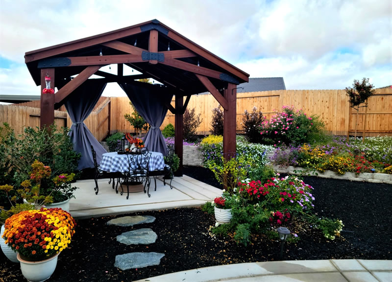 After one year, pergola with outdoor furniture, surrounded by garden flowers